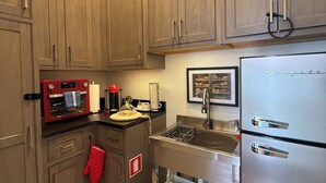 A kitchen with wooden cabinets, a stainless steel refrigerator, a red oven, and a sink.