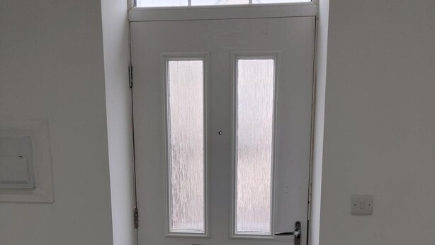 Une porte blanche avec deux fenêtres verticales et une poignée en métal.