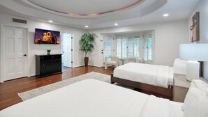 Ein Hotelzimmer mit Bett, Schreibtisch, Stuhl, Fernseher und einer Pflanze.