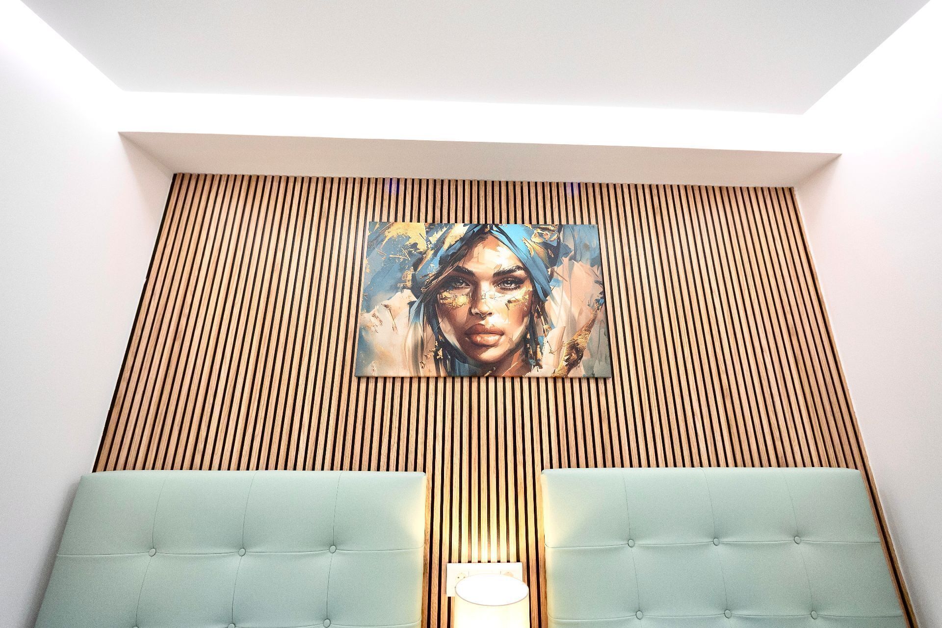 Una habitación con pared de listones de madera, una obra de arte grande y un cabecero verde esmeralda con capitonado.