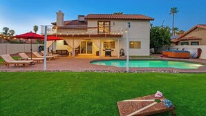 Une maison à deux étages avec une piscine, un espace salon extérieur et une terrasse couverte.