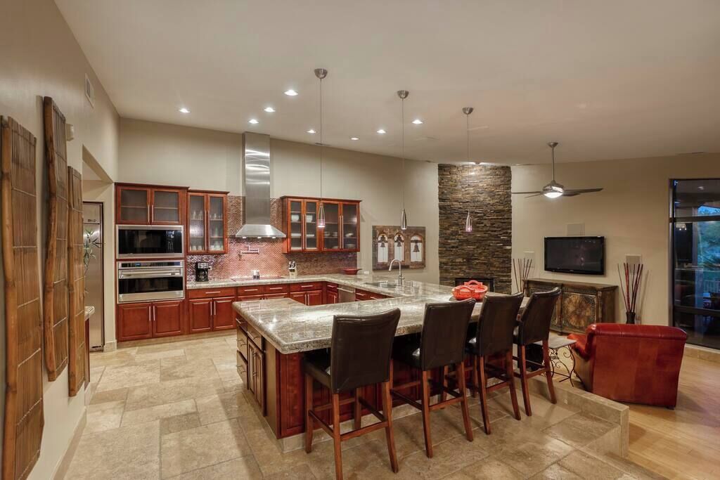 Una cocina moderna con una isla central, electrodomésticos integrados y una zona de comedor con taburetes de bar.