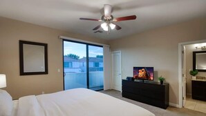 A hotel room with a bed, a TV, a ceiling fan, a dresser, and a sliding glass door to the balcony. - Private Patio & Grill, 10 minutes to Old Town (Scottsdale)