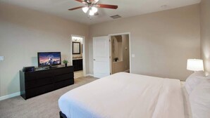 A bedroom with a bed, a ceiling fan, a TV on a dresser, and a door leading to another room. - Private Patio & Grill, 10 minutes to Old Town (Scottsdale)