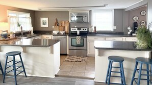 Una cucina moderna con isola, elettrodomestici in acciaio inossidabile e sgabelli da bar blu.