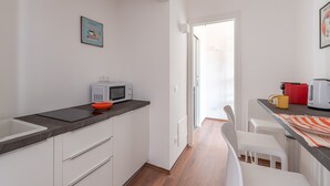 A modern kitchen with white cabinets, a black countertop, a microwave, and a red kettle. - Casa 73 by Wonderful Italy (Palermo)