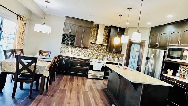 Una cocina moderna con armarios de madera oscura, una isla central e iluminación colgante.