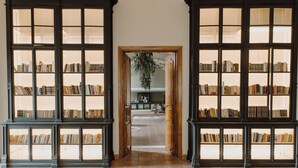 Una biblioteca con estanterías altas y un arco central que da a una zona de estar.