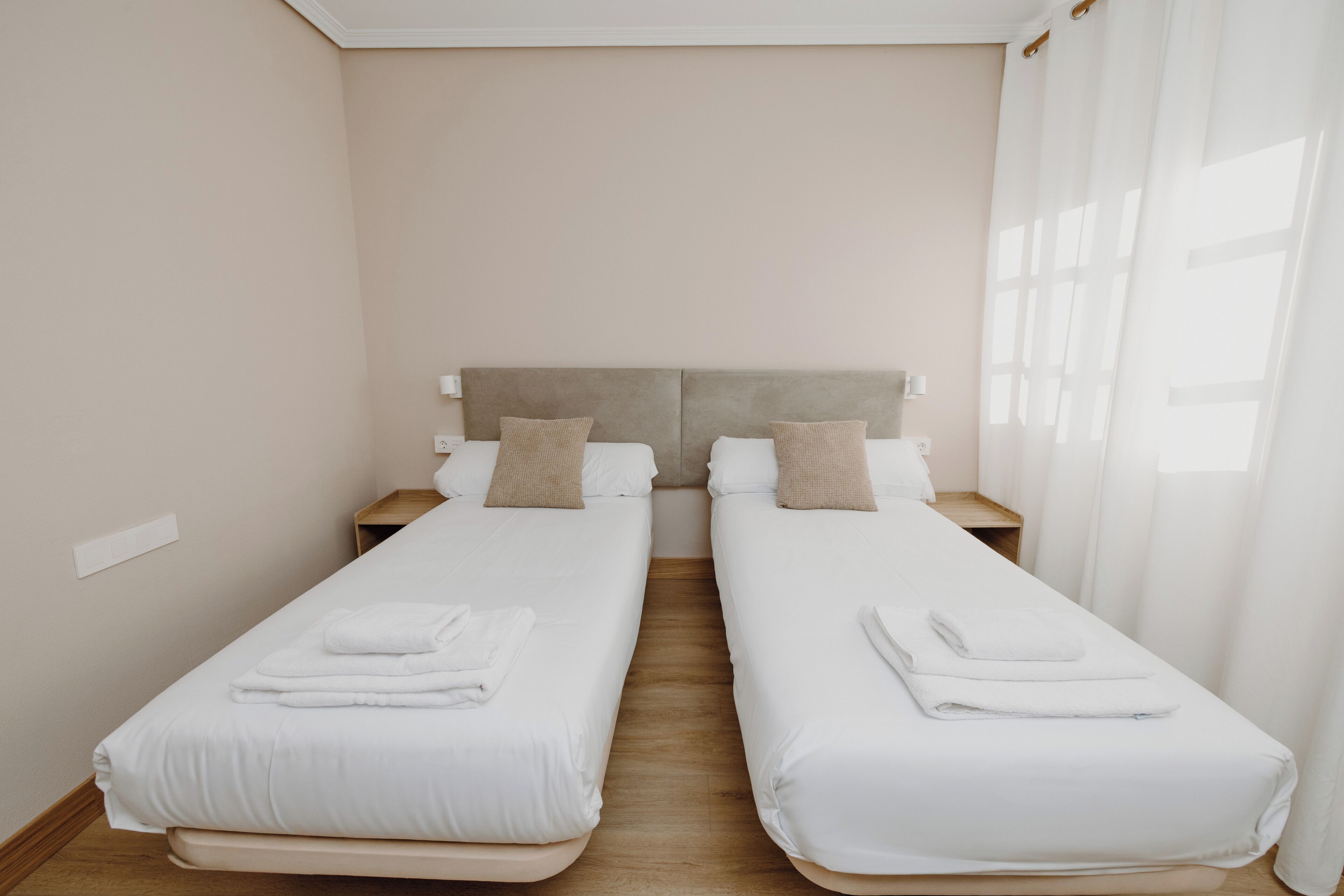A twin room with two single beds, wooden nightstands, and a neutral color scheme.