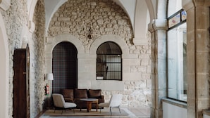 Una habitación amplia con un techo de piedra abovedado, una mesa de comedor de madera y un rincón de descanso acogedor con un sofá y sillones.