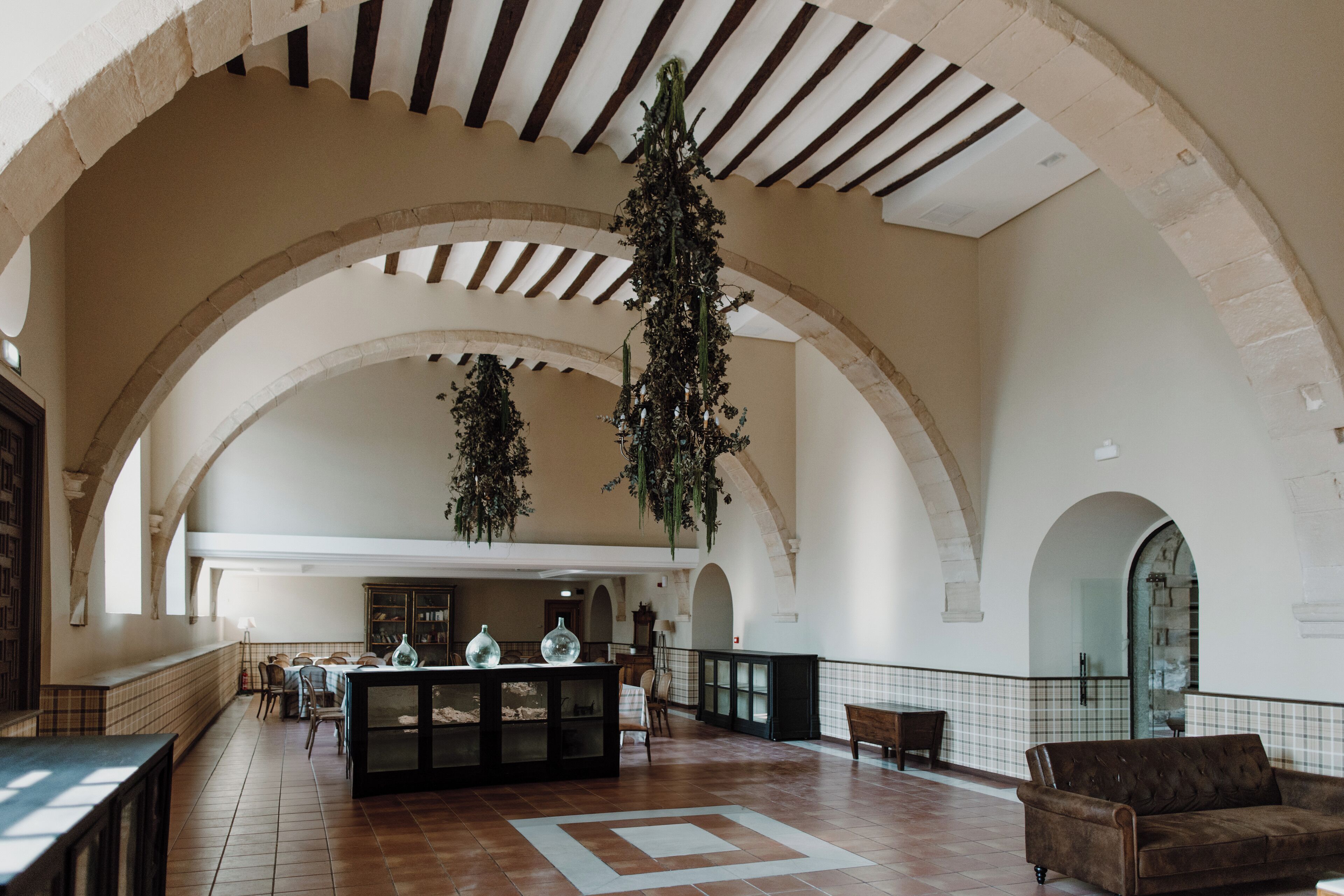 Un vestíbulo espacioso con techos altos, arcos y plantas colgantes.