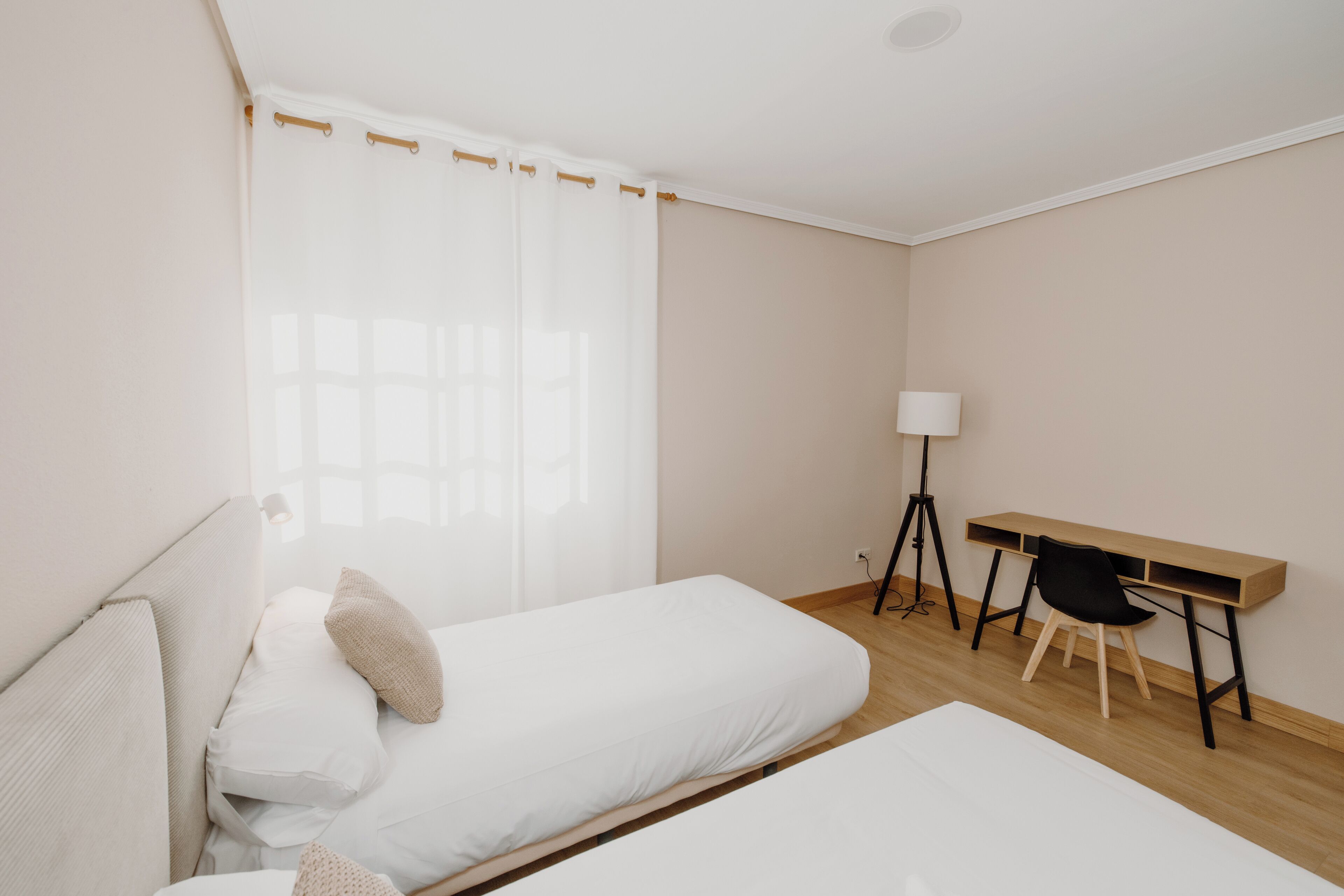 A bedroom with two beds, a desk, and a chair.