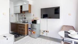 A compact kitchen with modern appliances, a dining area with a table and chairs, and a flat-screen TV mounted on the wall.