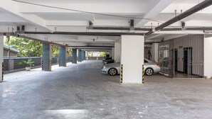 A covered parking area with concrete floors and columns, a gated entrance, and a vehicle parked inside.