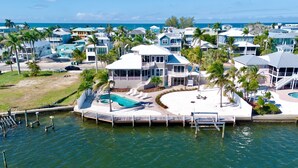 A coastal property with a swimming pool, multiple decks, and a view of the ocean.