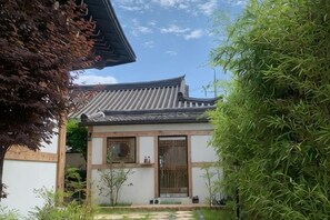 A traditional building with a tiled roof, a wooden door, and a small garden area with plants. - Adam Guesthouse (Gyeongju)