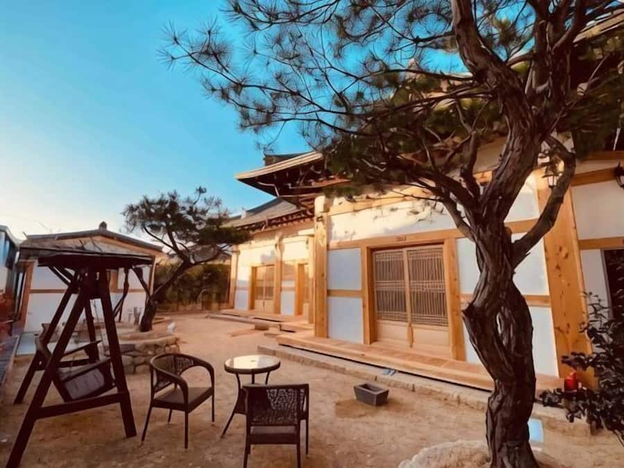 A traditional building with a wooden structure, a tree, and outdoor seating.