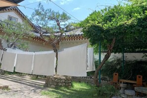 A traditional Japanese-style house with a covered outdoor area, stone benches, and a tree. - Adam Guesthouse (Gyeongju)