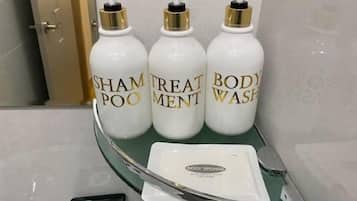 Three bottles of body wash on a glass shelf in a bathroom.