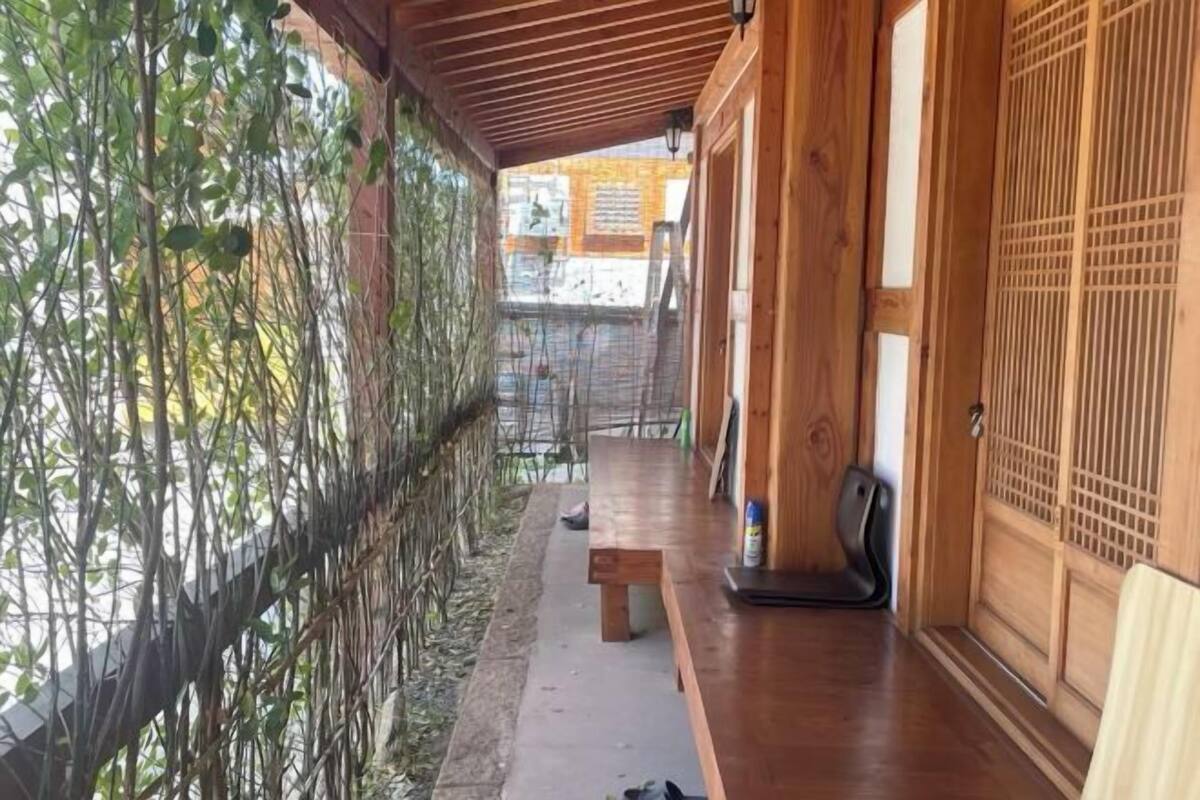 Une façade en bois avec un porche abrité, un banc et une porte coulissante traditionnelle.