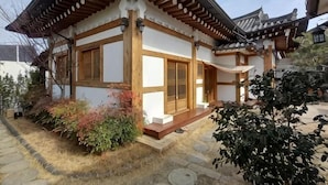 Un edificio japonés tradicional con tejado de tejas, vigas de madera y un camino de piedra.