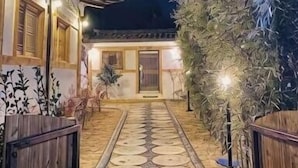 Un sendero conduce a un edificio de diseño tradicional, una cerca de madera y una entrada bien iluminada.