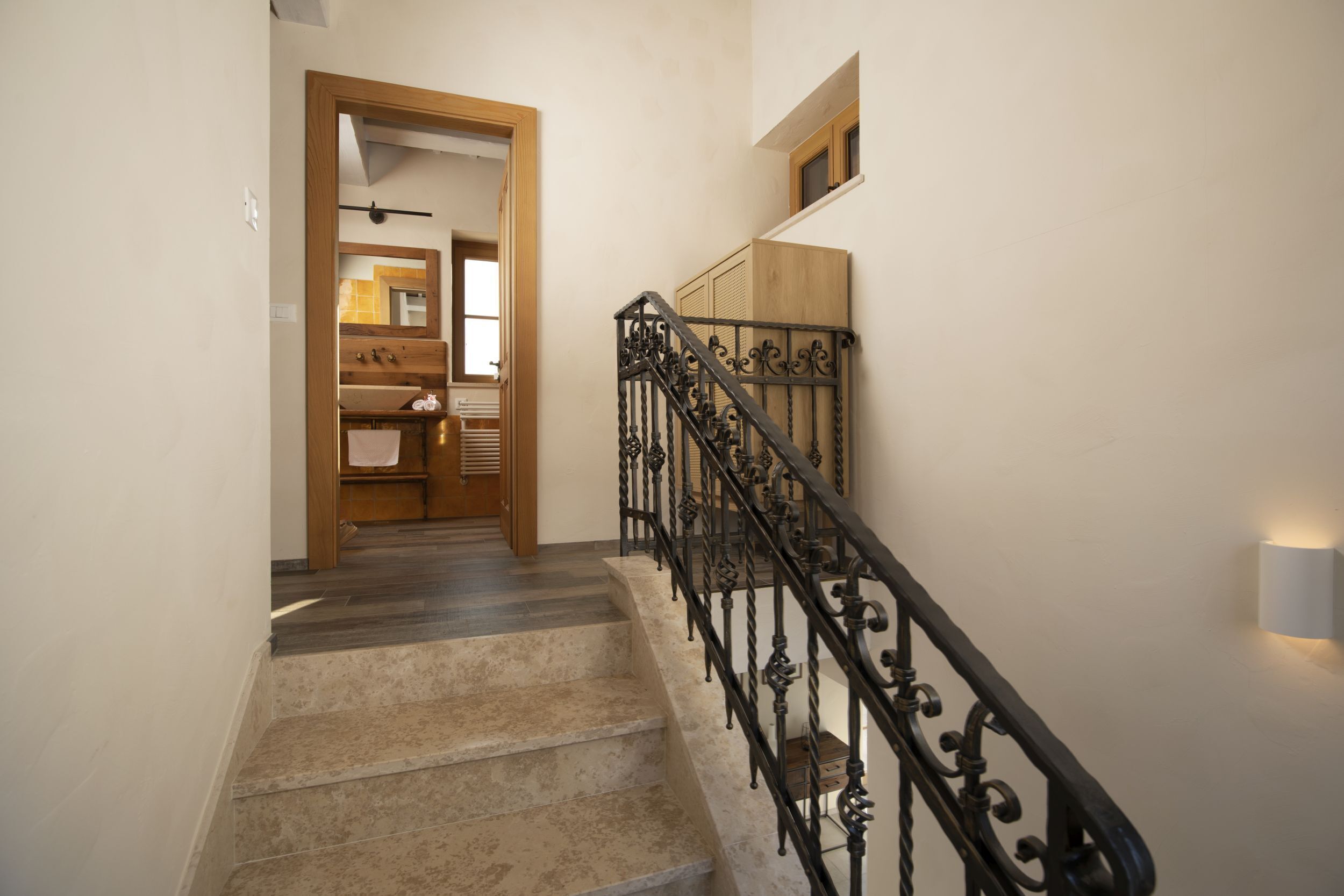 A staircase with a wooden handrail and a black wrought iron railing.