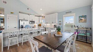 Una cocina moderna con armarios blancos, una isla central con asientos y una zona de comedor.