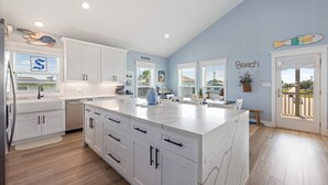 Una cocina moderna con armarios blancos, una isla grande y vistas al exterior.