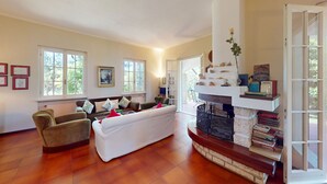 Un salon spacieux doté d’une cheminée, de sièges confortables et de grandes fenêtres.