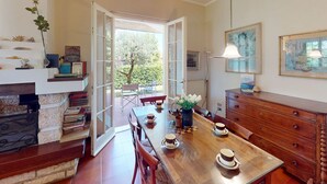 Un coin repas avec une table en bois, des chaises et une vue sur l’extérieur grâce à une porte ouverte.