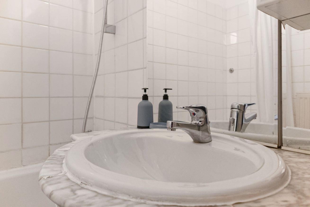Ein Badezimmer mit einem weißen Waschbecken, einem Spiegel und zwei Seifenspender.