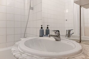 Une salle de bain avec un lavabo blanc, un miroir et deux bouteilles de savon.