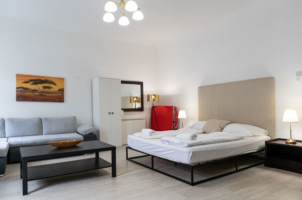 Une chambre d’hôtel moderne, équipée d’un lit, d’un canapé, d’une petite table, d’un miroir et d’un tableau accroché au mur.