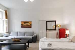 Une chambre d’hôtel équipée d’un canapé, d’un lit, d’une table, d’une armoire, d’un miroir et d’un tableau.