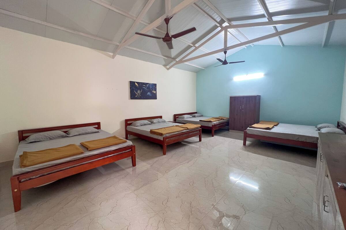 A room with four wooden beds, a wardrobe, and a ceiling fan.