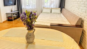 A room with a bed, a TV, a vase with flowers, and a brick wall. - Pensiunea Casa Veche Butuceni Orheiul vechi. (Butuceni)