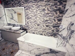 A bathroom with a stone wall, two sinks, a mirror, and a bathtub. - Pensiunea Casa Veche Butuceni Orheiul vechi. (Butuceni)