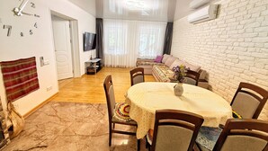A dining area with a round table, chairs, a clock, a television, and a sofa. - Pensiunea Casa Veche Butuceni Orheiul vechi. (Butuceni)