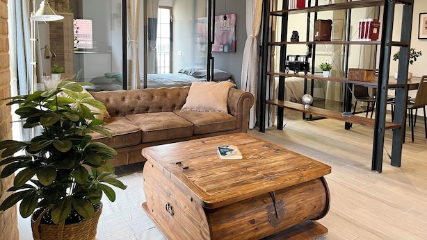 Un salon moderne avec un canapé d’angle, une table basse en bois et une cloison en verre.