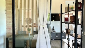 Une chambre moderne avec une porte en verre donnant sur un coin repas, un lit avec une serviette verte et une décoration minimaliste.