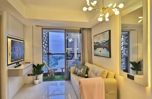 A modern living room with a sofa, TV, and a balcony with a view. - Staysanliving Goldcoast PIK (Jakarta)
