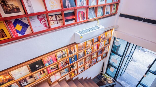 A staircase with bookshelves on either side, an air conditioning unit above, and a view of the street outside.