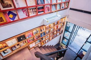 A staircase with bookshelves on either side, an air conditioning unit above, and a view of the street outside.