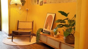 A room with a wooden chair, a lamp, a wall with a bulletin board, and potted plants.