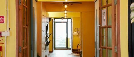 A hallway with wooden doors, a ceiling fan, and a light fixture.