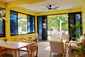 A room with yellow walls, large windows, and a ceiling fan. - Bed & Beach Hostel Karon (Karon)