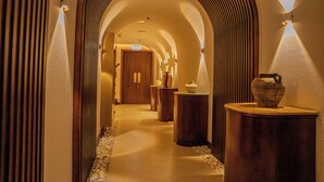 Un pasillo con techos abovedados y columnas de madera, que conduce a una puerta al final.