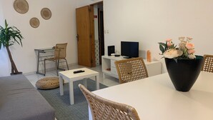 A living room with a sofa, a dining table, a TV, and a plant. - Vintage Chiado with Terrace (Lisboa)