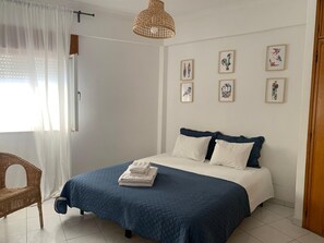 A bedroom with a bed, a chair, and artwork on the wall.